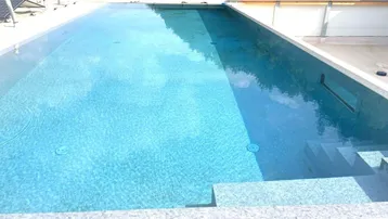 Großer Außenpool auf dem Dach mit klarem Wasser und umliegenden Fliesen.