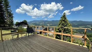 Geräumige Holzterrasse mit Sitzgelegenheiten und einem atemberaubenden Panoramablick auf die umliegende Berglandschaft.