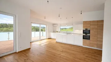 Moderne, offene Küche mit weißen Schränken, Holzelementen und integrierten Geräten.