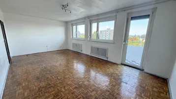 Helles Wohnzimmer mit Fischgrätparkettboden und Zugang zu einem sonnigen Balkon.