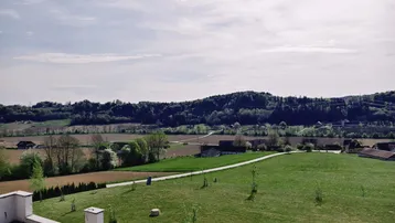 Weitläufiger Blick von der Terrasse über die grüne Landschaft und die umliegenden Felder.