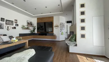 Geräumiges Wohnzimmer mit Holzboden, moderner Einrichtung und integriertem Mediensystem.