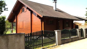 Charmantes Holzhaus mit Satteldach und gepflegtem Vorgarten, umgeben von einem Holzzaun.