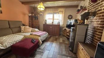 Gemütliches Wohnzimmer mit Kaminofen, Sofa und Holzbalkendecke.