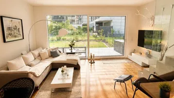 Helles Wohnzimmer mit großem Ecksofa, Holzboden und Zugang zum Garten.
