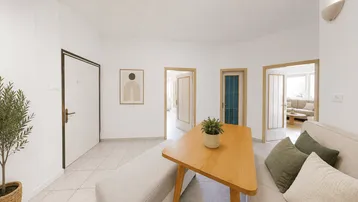 Heller Wohnbereich mit Fliesenboden und Zugang zu mehreren Zimmern, modern eingerichtet.