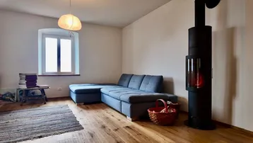 Gemütliches Wohnzimmer mit modernem Kaminofen, bequemer Couch und Holzboden.