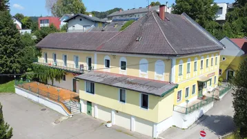 Luftaufnahme des großen Gebäudekomplexes mit mehreren Etagen und Satteldach in ländlicher Umgebung.
