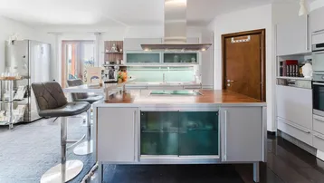 Moderne Küche mit Kücheninsel, Holzarbeitsplatte und integrierten Geräten.