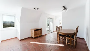 Gemütlicher Essbereich mit Terrakottafliesen, Holztisch und Blick ins Grüne.