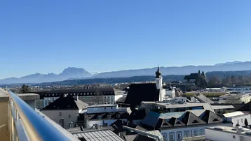 Panoramablick über die Stadt mit historischen Gebäuden und majestätischen Bergen im Hintergrund.