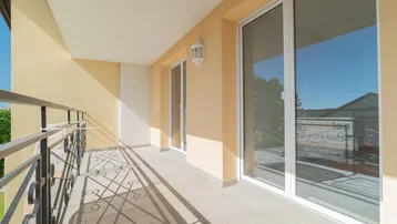 Heller Balkon mit Fliesenboden und schmiedeeisernem Geländer, bietet eine weite Aussicht.
