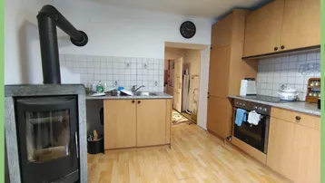 Rustikale Küche mit Holzschränken, Fliesenrückwand und einem gemütlichen Holzofen.