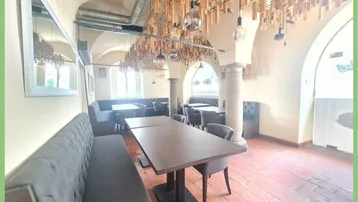 Geräumiger Gastraum mit hohen Gewölbedecken, Terrakottaboden und moderner Holzdekoration an der Decke.