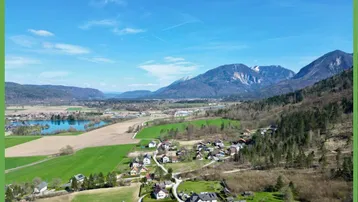 Luftaufnahme einer malerischen Landschaft mit See, Bergen und einem charmanten Dorf.