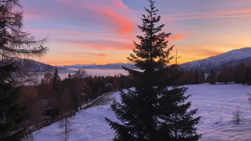 Malerische Winterlandschaft bei Sonnenuntergang mit schneebedeckten Feldern und farbenprächtigem Himmel.