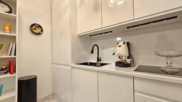 Moderne, weiße Küche mit Hochglanzfronten, schwarzer Spüle und integriertem Induktionskochfeld.