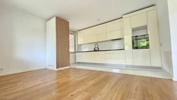 Moderne, offene Küche mit glänzenden Fronten und Holzboden, integriert in einen hellen Wohnbereich.