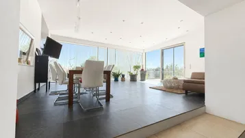 Heller, offener Wohn- und Essbereich mit großen Fenstern, Zugang zur Terrasse und modernen Möbeln.