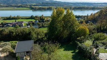 Panoramablick über die Landschaft mit einem Fluss, umgeben von grünen Hügeln und vereinzelten Häusern.