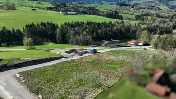 Luftaufnahme eines grünen Grundstücks mit markierter Fläche und weitem Blick auf die umliegende Hügellandschaft.