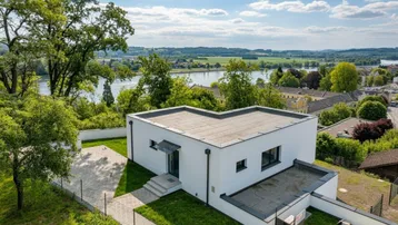 Moderne weiße Villa mit Flachdach und Panoramablick auf den Fluss und die umliegende Landschaft.