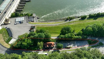 Luftaufnahme des Grundstücks mit angrenzendem Fluss, Damm und umliegender grüner Landschaft.