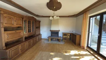 Geräumiges Wohnzimmer mit Holzboden, Kamin und großen Fenstern zum Garten.