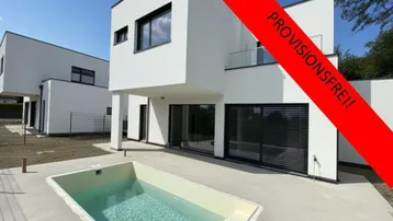 Modernes weißes Haus mit kleinem Pool und minimalistischer Architektur, umgeben von einer gepflasterten Terrasse.