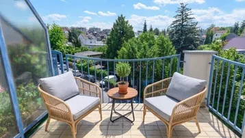 Heller Balkon mit Korbmöbeln und weitem Blick über die grüne Umgebung.