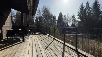 Geräumige Holzterrasse mit Blick auf den umliegenden Wald und viel Sonnenlicht.