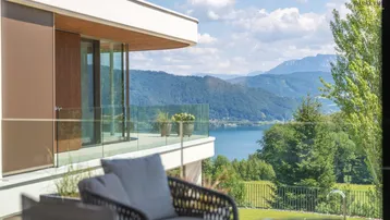 Geräumiger Balkon mit Glasgeländer und atemberaubendem Blick auf den See und die Berge.