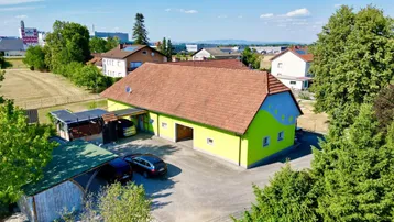 Luftaufnahme des Gebäudes mit leuchtend grüner Fassade und rotem Ziegeldach in ländlicher Umgebung.