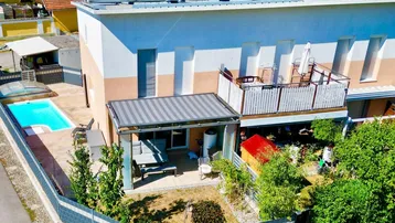 Luftaufnahme des modernen Hauses mit Pool, Garten, Balkon und Solaranlage auf dem Dach.