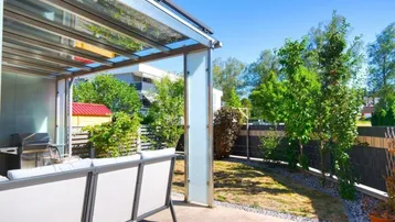 Überdachte Terrasse mit Gartenmöbeln und Blick ins Grüne, ideal für entspannte Stunden im Freien.