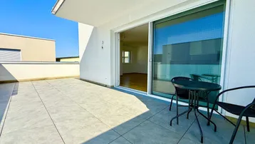 Helle, geräumige Dachterrasse mit Fliesenboden und Blick auf die Umgebung, ideal für Entspannung.
