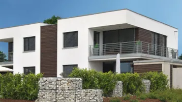 Moderne Wohnanlage mit weißer Fassade, Holzdetails und großen Balkonen, umgeben von gepflegter Grünfläche und Gabionenmauern.