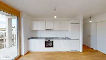 Moderne Einbauküche mit weißen Schränken, Holzboden und Zugang zu einem Balkon.