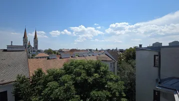 Blick über die Dächer der Stadt mit Kirchtürmen und blauem Himmel an einem sonnigen Tag.
