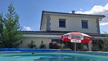 Außenansicht des Hauses mit privatem Swimmingpool und Sonnenschirm im Gartenbereich.