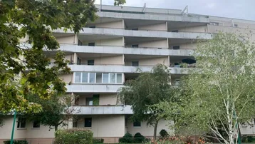 Mehrstöckiges Wohngebäude mit zahlreichen gestaffelten Balkonen und einer gepflegten Grünanlage im Vordergrund.