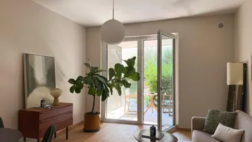 Helles Wohnzimmer mit Holzboden, modernen Möbeln und direktem Zugang zu einer Außenterrasse.