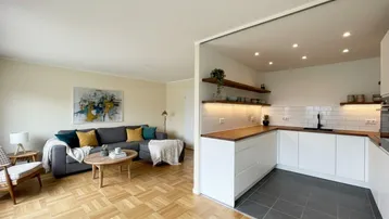 Heller offener Wohnbereich mit Parkettboden und moderner Küche mit Holztheke.