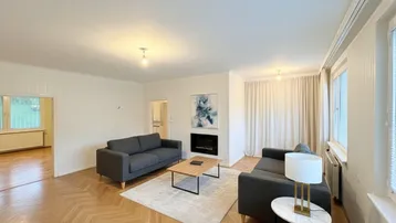 Helles Wohnzimmer mit Fischgrätparkett, modernen Sofas und einem dekorativen Kamin.