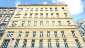 Historisches Mehrfamilienhaus mit klassischer Fassade und vielen Fenstern unter blauem Himmel.
