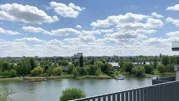 Weitläufiger Blick über den See und die grüne Umgebung von einem Balkon aus.