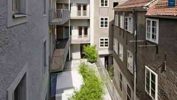 Blick auf den begrünten Innenhof mit Balkonen und den Fassaden der umliegenden Gebäude.