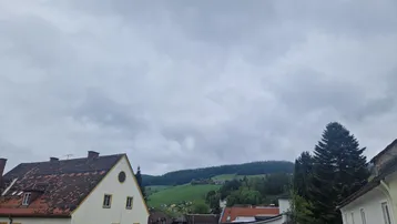 Weitläufiger Blick auf grüne Hügel und die umliegende Landschaft unter bewölktem Himmel.