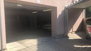 Eingang zur Tiefgarage mit Stellplätzen und überdachtem Bereich für Mülltonnen.