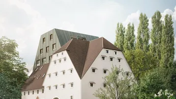 Historisches Gebäude mit modernem Anbau, umgeben von Bäumen und Grünflächen.